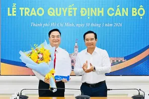 Chairman of the HCMC People’s Committee Nguyen Van Duoc presents appointment decision and congratulates Mr. Hoang Vu Thanh with flowers. (Photo: SGGP)