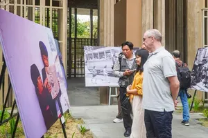 Visitors admire a photograph that evokes childhood memories at the “Vietnam Crossroads” exhibition. (Photo: SGGP)