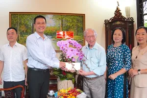 Deputy Head of the HCMC Party Committee's Propaganda and Mass Mobilization Commission Nguyen Viet Long (2nd, L) offers a gift to Prof. Dr. Dao Van Luong (3rd, R). (Photo: SGGP)