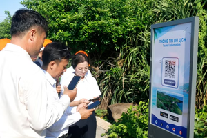 Tourists scan the QR Code to access travel information at the sovereignty flagpole of Phu Quy Special Zone in Lam Dong province. (Photo: VNA)