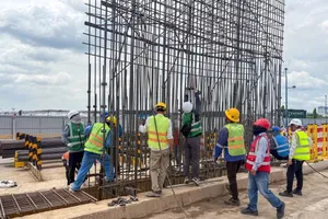 Workers lower a reinforcing steel cage for the diaphragm wall at ST10 station (Pham Van Bach Station). (Photo: SGGP)