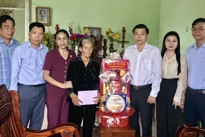 Head of the Internal Affairs Commission of the Ho Chi Minh City Party Committee, Tran Van Tuan (3rd,R), visits war invalid Nguyen Thi Muoi (4th,L). (Photo: SGGP)