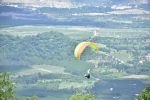 A paraglider pilot descends from La Bàn Peak to the landing zone at the base of the mountain. (Photo: SGGP)