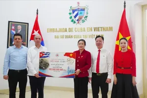 Chairwoman of the Central Committee of the Viet Nam Red Cross Society Do Thi Thu Thao presents a symbolic board representing VND100 billion (around US$3.8 million) in support to Cuban Ambassador to Viet Nam Rogelio Polanco Fuentes. (Photo: SGGP)
