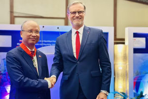 Authorised by the French President, French Ambassador to Vietnam Olivier Brochet gives the noble order to Former Vietnamese Ambassador to France Dinh Toan Thang at a ceremony in Hanoi on August 26 (Photo: VNA)
