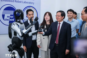 Deputy Prime Minister Ho Quoc Dung and delegates view a robot at the centralised practice centre of the University of Engineering and Technology, Vietnam National University, Hanoi. (Photo: VNA)
