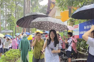Thí sinh điểm thi THPT Trưng Vương ra về trong cơn mưa tầm tã. Ảnh: THU TÂM