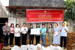 代表团将辅助建造大团结屋的经费赠予卡迪翁大娘(麻族同胞)家庭，后面是她一家的破旧房子。