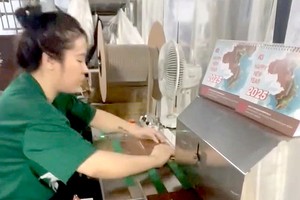 印刷厂的员工正忙着为客户印刷日历。