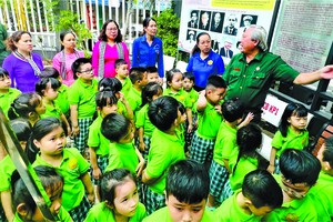 新平郡第十一坊退伍军人协会主席黄柯迎接学生们前来参观传统室和胡志明文化空间。