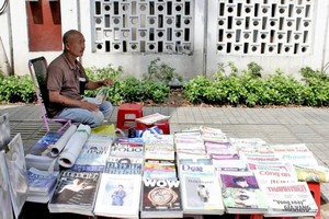 雄叔每天风雨不改在路边摆摊卖报。
