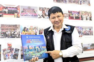 摄影师段怀忠与摄影集《胡志明市-50年英雄赞歌》。