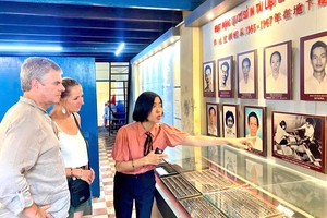 龙长青给游客介绍地下印刷组领导与组员遗照。