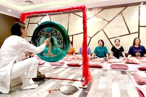 技术人员示范颂钵的音疗来给客人体验。