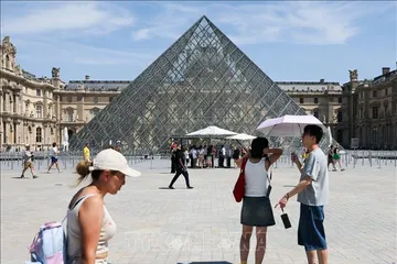 Du khách che ô chống nắng khi tham quan viện bảo tàng Louvre ở Paris, Pháp ngày 25-6. Ảnh: THX/TTXVN