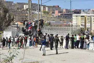 Người di cư trèo qua hàng rào biên giới để vào vùng lãnh thổ Ceuta của Tây Ban Nha từ thành phố Fnideq, Maroc. Ảnh: THX/TTXVN phát