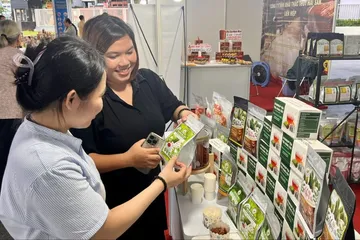 Người tiêu dùng chọn mua mứt đặc sản như mãng cầu, dừa non... tại một gian hàng ở Nhà thi đấu Phú Thọ, chiều 23-10. Ảnh: GIA HÂN