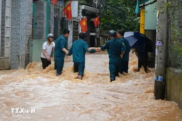 Lực lượng dân quân phường Phước Tân, thành phố Đồng Nai cố băng qua dòng nước chảy xiết để hỗ trợ người dân. (Ảnh: Lê Xuân/TTXVN)