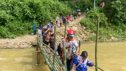 Học sinh được lực lượng chức năng hỗ trợ qua cầu tạm để kịp đến trường trong buổi học đầu tuần