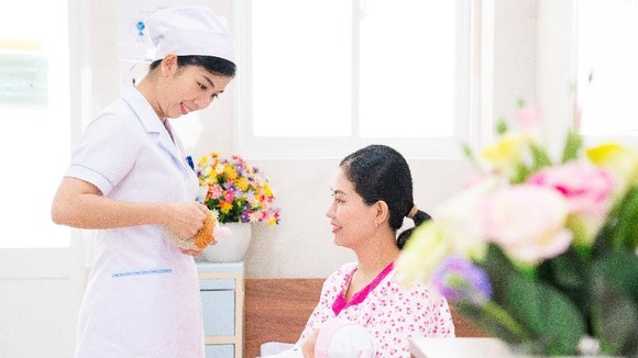 Nữ hộ sinh tư vấn cho sản phụ về tư thế cho con bú.