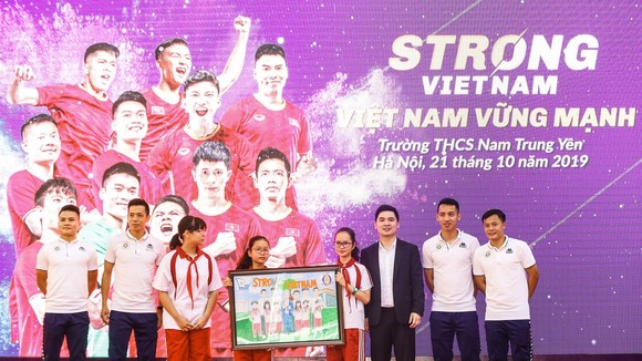 Các cầu thủ CLB bóng đá Hà Nội và Trưởng Ban tổ chức chương trình “Strong Vietnam” Đỗ Vinh Quang nhận quà là bức tranh từ các em học sinh THCS Nam Trung Yên