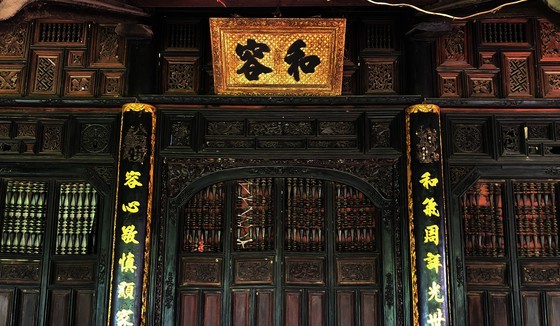 A horizontal lacquered board engraved with characters , “Hoa Dung”, is hung over a door aiming at teaching the family’s members to live in peace with each other.