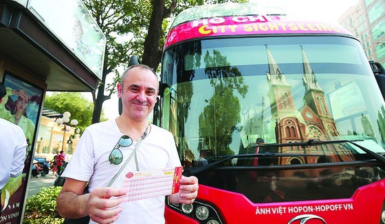 A foreign tourist buys a fare for hop-on hop-off tour in HCMC (Photo: SGGP)