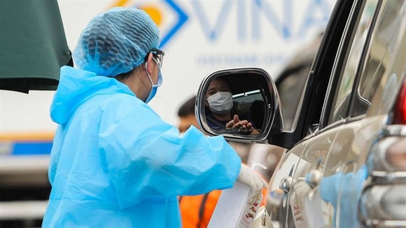 A medical worker sprays a hospital visitor with sanitiser. — Photo nld.com.vn