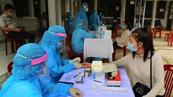 Medical workers conduct quick tests for people returning from COVID-19-hit regions (Photo: VNA)