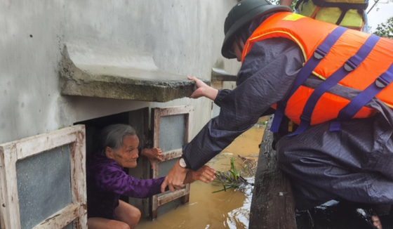 A rescue worker take an old woman out from her flooded house in Quang Binh Province (Photo: SGGP)