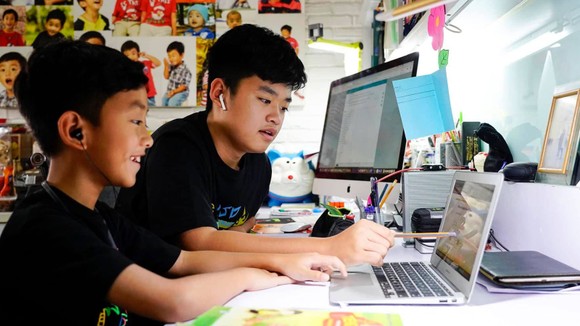 Em Nguyễn Huỳnh Thông, lớp 3 trường Võ Thị Sáu đang làm quen với cách học trực tuyến với sự hướng dẫn của người anh Nguyễn Huỳnh Bách, lớp 7 trường Đinh Thiện Lý. Ảnh: THANH TÙNG
