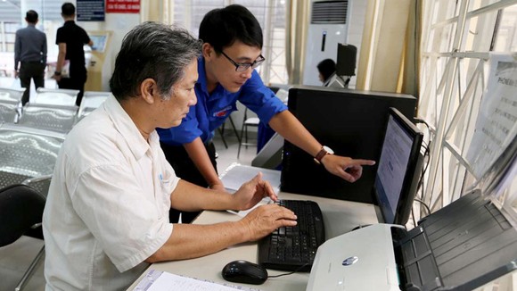 Công chức UBND quận Bình Thạnh hướng dẫn người dân thực hiện đăng ký hồ sơ qua mạng. Ảnh: Thái Phương