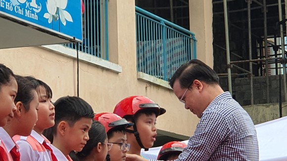 Thầy Trần Nguyễn Minh Thành trao tặng mũ bảo hiểm cho các em học sinh lớp 5 có hoàn cảnh gia đình khó khăn
