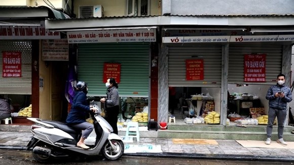 Stores on Hanoi's Luong Van Can Street half close their doors, only serve take-aways or online orders due to the impact of COVID-19 (Photo: VNA)