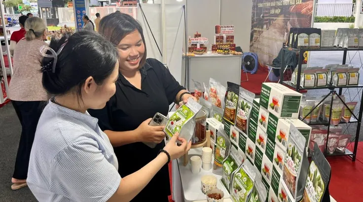 Người tiêu dùng chọn mua mứt đặc sản như mãng cầu, dừa non... tại một gian hàng ở Nhà thi đấu Phú Thọ, chiều 23-10. Ảnh: GIA HÂN