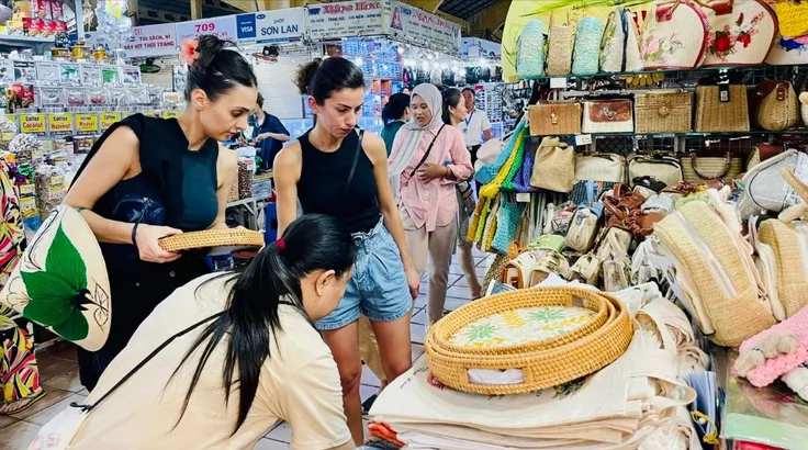 Du khách nước ngoài chọn mua đồ lưu niệm tại chợ Bến Thành (TPHCM). Ảnh: THI HỒNG