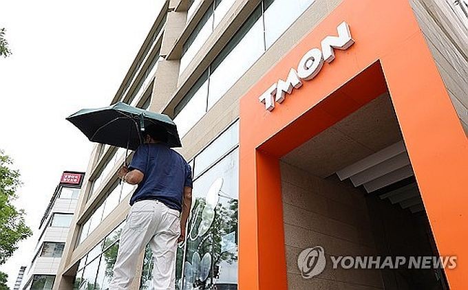 7月24日，一名男性撑伞走过位于首尔江南区的TMON总部大楼。（图：韩联社）
