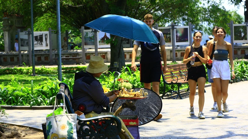 Trong khi nhiều người Hà Nội tránh ra đường trong ngày nắng gắt thì du khách quốc tế không ngại "đội" nắng dạo phố. Ảnh: HÀ NGUYỄN