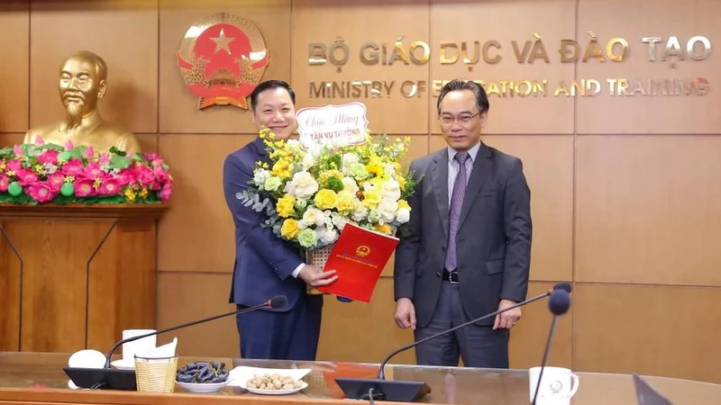 Thứ trưởng Bộ GD-ĐT Hoàng Minh Sơn (bên phải) trao quyết định và tặng hoa chúc mừng tân Vụ trưởng Vụ Giáo dục đại học Nguyễn Tiến Thảo