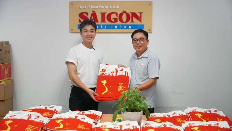 Anh Đinh Xuân Dương, CEO FlyG Entertainment (áo trắng) tặng Báo Sài Gòn Giải Phóng 200 túi xách in hình bản đồ đất nước. Ảnh: VIỆT NGA
