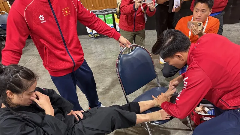 Nhân viên y tế Lê Viết Lãm giúp võ sĩ pencak silat vượt qua cơn đau sau khi vừa thi đấu trận chung kết. Ảnh: MINH CHIẾN