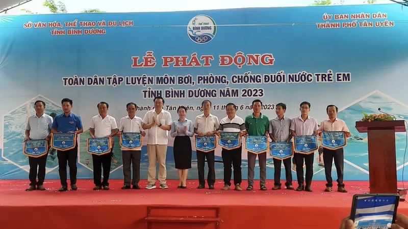 Ông Cao Văn Chóng - PGĐ Sở Văn hóa, Thể thao và Du lịch và bà Nguyễn Thị Kim Nguyên - Phó Chủ tịch UBND thành phố Tân Uyên tặng cờ lưu niệm cho các đơn vị tham dự Lễ Phát động