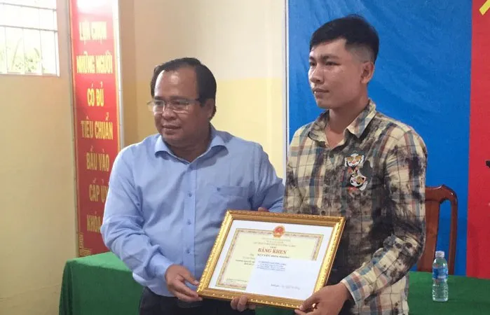 Phó Chủ tịch UBND tỉnh Cà Mau Nguyễn Minh Luân (trái) trao Bằng khen cho anh Nguyễn Hiền Phong