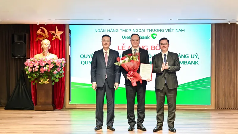 Ông Phạm Quang Dũng, Ủy viên Ban Thường vụ Đảng ủy, Phó Thống đốc NHNN (ngoài cùng bên trái) và ông Nguyễn Thanh Tùng, Ủy viên BCH Đảng bộ Chính phủ, Bí thư Đảng ủy, Chủ tịch HĐQT Vietcombank (ngoài cùng bên phải) trao quyết định và tặng hoa chúc mừng ông Lê Quang Vinh - tân Tổng Giám đốc Vietcombank