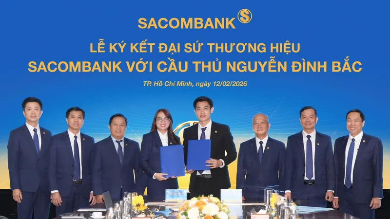 Cầu thủ Nguyễn Đình Bắc (phải) và bà Nguyễn Thị Kiều Anh (trái), Phó Tổng giám đốc SACOMBANK thực hiện nghi thức ký kết Thỏa thuận Đại sứ thương hiệu dưới sự chứng kiến của Ban lãnh đạo Ngân hàng