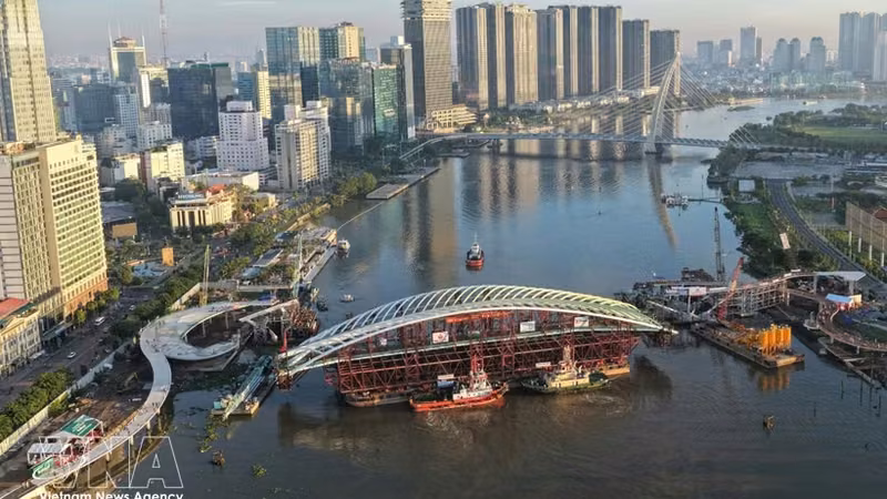装载主跨结构的驳船就位于西贡河步行桥项目合龙位置全景图。图：越通社