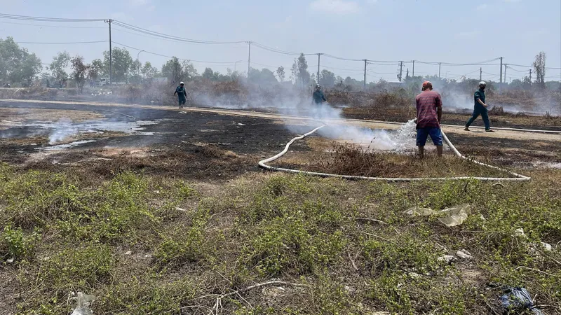Lực lượng chức năng xã Tân Vĩnh Lộc đang khống chế đám cháy do các đối tượng đốt rác gây cháy lan tại khu đất trống trên đường Trần Hải Phụng, xã Tân Vĩnh Lộc. Ảnh: TK