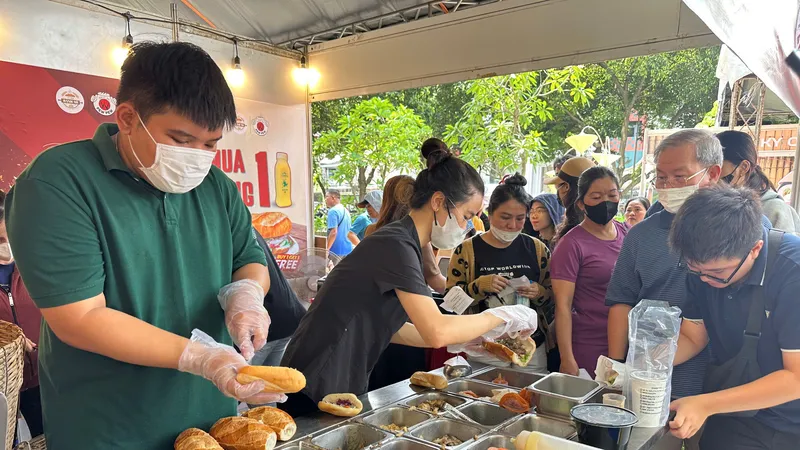 Người dân xếp hàng mua và thưởng thức bánh mì trong chiều và tối 21-3, tại công viên Lê Văn Tám