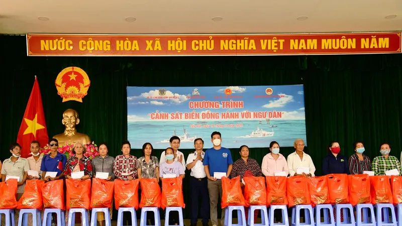 Thiếu tướng Đỗ Hồng Đó, Chính ủy Bộ Tư lệnh Vùng Cảnh sát biển 3 (người mặc quân phục đứng giữa) cùng lãnh đạo chính quyền địa phương trao quà cho gia đình chính sách, ngư dân. Ảnh: TRẦN YÊN