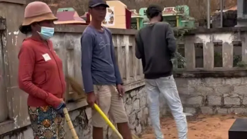 Nhóm người cầm theo chổi tự ý dọn dẹp mồ mả rồi xin tiền người nhà. Ảnh cắt từ video